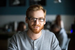 stock-photo-portrait-of-smiling-red-haired-millennial-man-looking-at-camera-sitting-in-caf-or-coffeeshop-250nw-1194497251 (1)